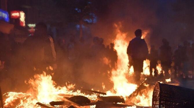 Aktivisten stehen im Hamburger Schanzenviertel vor einer brennenden Barrikade. Foto: Boris Roessler