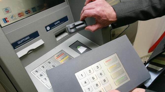 Ein Mitarbeiter einer Sparkasse demonstriert an einem Geldautomaten »Skimming«- Technik. Foto: Thomas Frey/Illustration