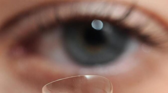 Eine Kontaktlinse wird vor das Auge einer Frau gehalten. Im Auge einer Patientin haben britische Ärzte 27 Kontaktlinsen gefun