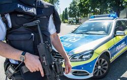Ein Polizist steht mit seiner Waffe in Esslingen auf einem Zufahrtsweg zur Friedrich-Ebert Schule. Foto: Sven Friebe