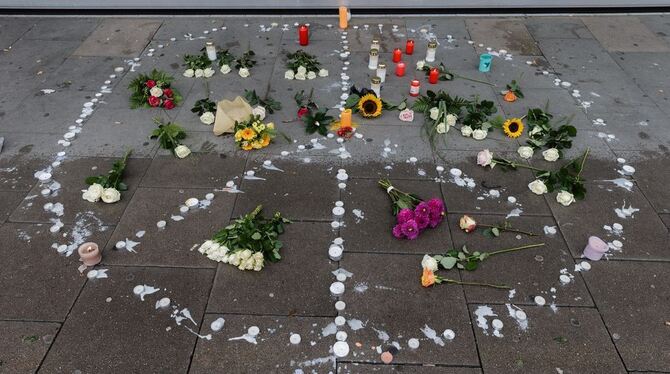 Blumen und Kerzen liegen am 29.07.2017 in Hamburg in einem Peace-Zeichen auf dem Bürgersteig vor dem Supermarkt, in dem am 28.07
