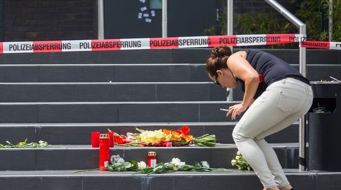 Eine Frau legt vor dem Eingang des Clubs »Grey« in Konstanz Blumen nieder.