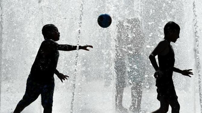 Kinder spielen in Frankfurt am Main bei hochsommerlichen Temperaturen in einem Springbrunnen. Foto: Arne Dedert