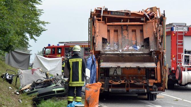 Feuerwehrkräfte arbeiten auf einer Straße bei Nagold (Baden-Württemberg) an einer Unfallstelle, an der ein Müllwagen auf ein Aut