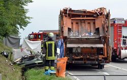Feuerwehrkräfte arbeiten auf einer Straße bei Nagold (Baden-Württemberg) an einer Unfallstelle, an der ein Müllwagen auf ein Aut