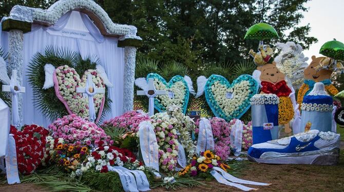 Ein Meer aus Kränzen, Blumen und Gestecken sowie bunte Mickey-Maus-Figuren mit Luftballons sind nach der Trauerfeier und Beerdig