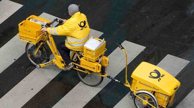 Ein Briefträger der Deutschen Post fährt in Stuttgart mit einem Fahrrad (E-Bike) über einen Zebrastreifen. Foto: Sebastian Kahne