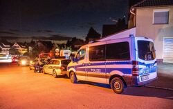 Polizeifahrzeuge stehen in Villingendorf auf einer Straße in einem Wohngebiet. In einem Wohnhaus sind ein Mann, eine Frau und ei