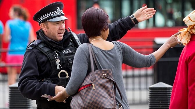 Eine Passantin holt sich in London bei einem Polizisten Rat. Großbritannien erhöht nach dem Bombenattentat in einer U-Bahn mit 2