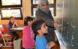 Lehrerin Nesrin Abdulwahed zeigt dem sechsjährigen Hassan und der achtjährigen Roha  Buchstaben der arabischen Schrift. Das late