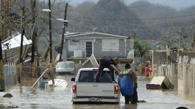 Bewohner beladen einen Pkw in einer überfluteten Straße in Toa Baja (Puerto Rico) mit ihren geretteten Habseligkeiten. Foto: