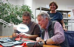 Techniker Peter Rath (links) repariert den MP3-Player von Fritz Lauer. Organisatorin Barbara Vangerow sorgt für die Bewirtung im
