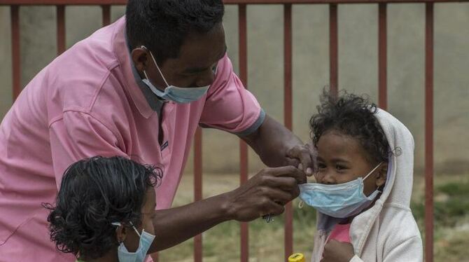 Ein Mann in Antananarivo legt einem Kind einen Mundschutz an. Die hochansteckende Lungenpest breitet sich auf der Insel aus.