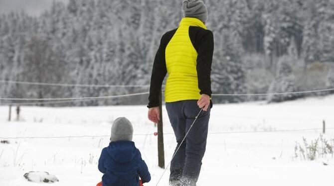 Ein Mann zieht bei Hofsgrund seinen Sohn auf einem Schlitten durch den Schnee. Foto: Patrick Seeger