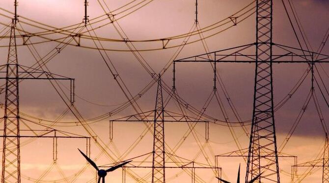 Strommasten und Windräder heben sich wie Scherenschnitte vom farbenprächtigen Abendhimmel ab. Foto: Patrick Pleul