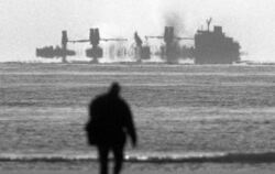 Nur schemenhaft ist der havarierte noch immer brennende Holzfrachter "Pallas" am Dienstag (17.11.1998) vom Strand der Nordsee