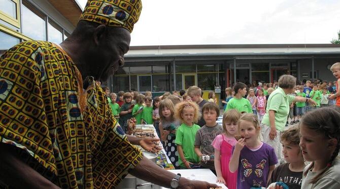 Guten Appetit wünscht Kobna Anan jedem der 120 Kinder zum Festmahl und reicht Joloff, das traditionelle Essen aus Ghana, das in Guten Appetit wünscht Kobna Anan jedem der 120 Kinder zum Festmahl und reicht Joloff, das traditionelle Essen aus Ghana, das in