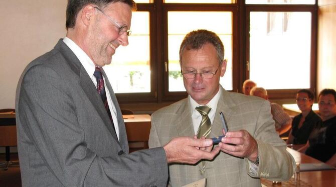 Die goldene Ehrennadel des Gemeindetags im Blick: Wilfried Schneider bekommt sie aus den Händen von Bürgermeister Helmut Knorr (