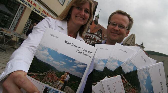 Sylvie Lemnitz-Eppler und Torsten Clement zeigen auf dem Marktplatz den neuen Wanderführer der Stadt Bad Urach.