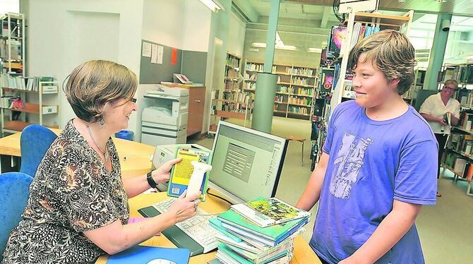 Die diplomierte Bibliothekarin Tanja Schleyerbach registriert Bücher, die der 13-jährige Kai ausleihen will.
