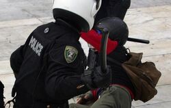 Knüppel frei: Ein griechischer Polizist in Athen droht einem am Boden liegenden Demonstranten mit einem Schlagstock (Archivbi