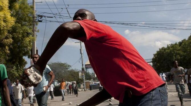 Ein Haitianer schleudert in Port au Prince einen Stein auf die dort stationierten UN-Blauhelme.