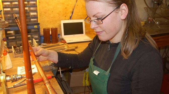 Anne Schneider zeigt an ihrer Werkbank zwei verzierte Pfeifen. GEA-FOTO: IST