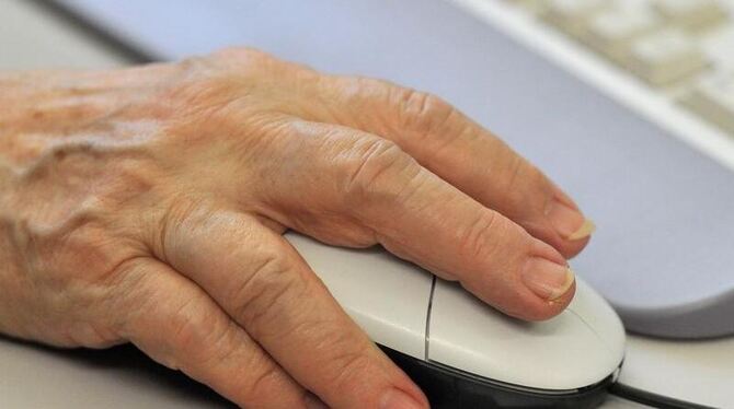 Die Hand einer älteren Frau auf einer Computermaus