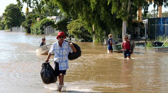 Einwohner der australischen Stadt Rockhampton waten durch eine überflutete Straße.