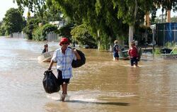 Einwohner der australischen Stadt Rockhampton waten durch eine überflutete Straße.