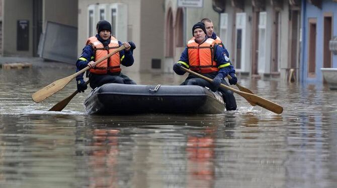 Mitglieder des Technischen Hilfswerks paddeln mit einem Schlauchboot durch die überflutete Altstadt von Wertheim.