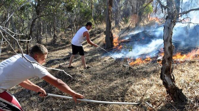 Zwei Australier versuchen die sich ausbreitenden Flammen zu stoppen. Zwei Australier versuchen die sich ausbreitenden Flammen zu stoppen.