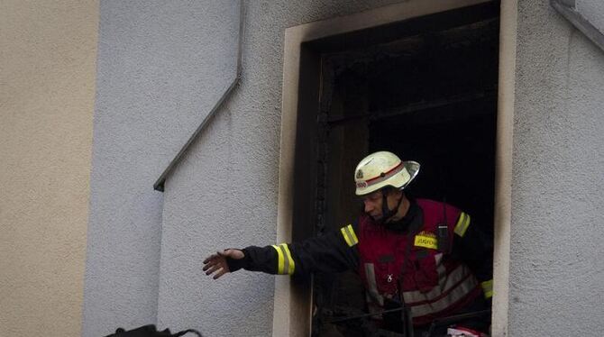 Ein Feuerwehrmann wirft nach einem Brand einen Gegenstand aus dem Unglückshaus.