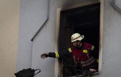 Ein Feuerwehrmann wirft nach einem Brand einen Gegenstand aus dem Unglückshaus.