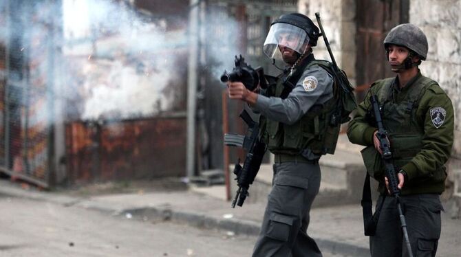 Ein israleischer Soldat schießt mit Tränengas auf Palästinensische Steinewerfer, nachdem es in Beit Omar zu Unruhen gekommen war