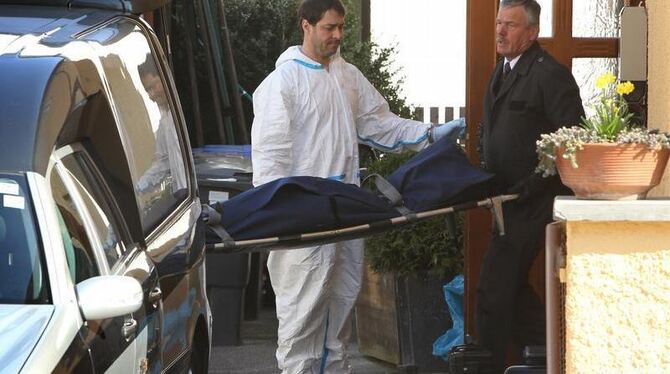 Mitarbeiter eines Bestattungsunternehmens tragen in Krailling ein totes Kind aus dem Haus.