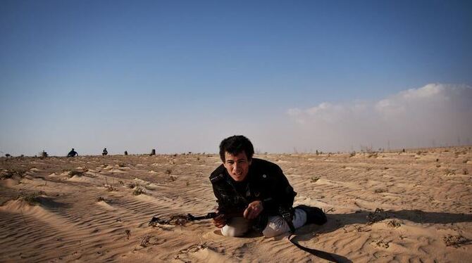 Ein libyscher Rebell in Adschdabija geht in Deckung, als seine Stellung von Gaddafi-Truppen bombardiert wird.