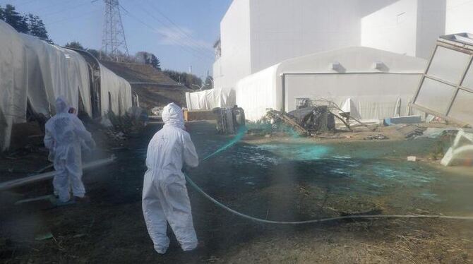 Helfer sprühen Kunstharz auf dem Gelände des havarierten Atomkraftwerkes im japanischen Fukushima aus, um radioaktiven Staub Helfer sprühen Kunstharz auf dem Gelände des havarierten Atomkraftwerkes im japanischen Fukushima aus, um radioaktiven Staub