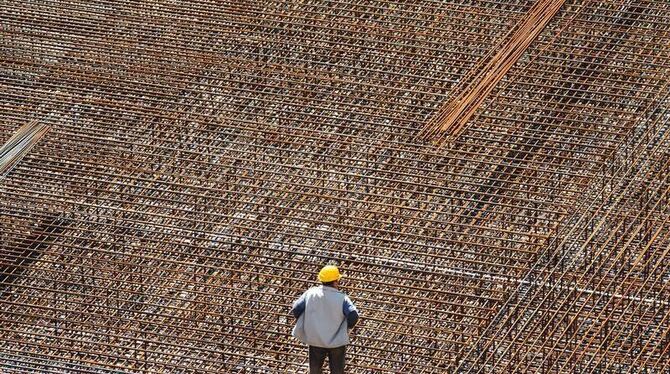 Ein Bauarbeiter auf einem Netz aus Baustahl für das Fundament eines Gebäudes. Die bundesweit rund 700 000 Beschäftigten des B