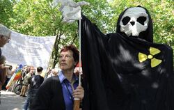 Eine Demonstrantin trägt in München eine übergroße Marionette mit Totenschädel und dem Symbol für Radioaktivität.