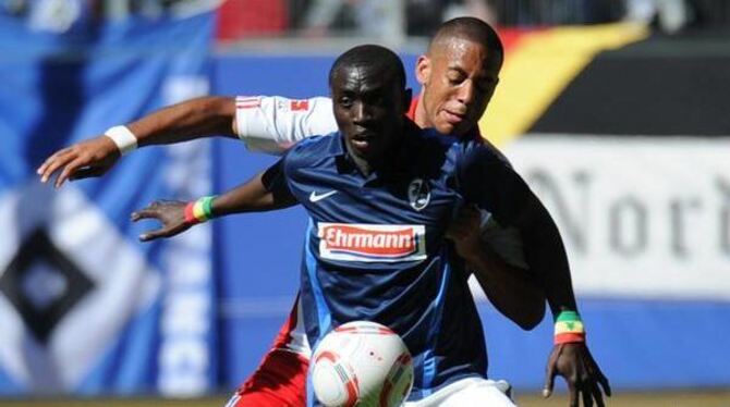 Freiburgs Doppeltorschütze Papiss Demba Cissé setzt sich spielend gegen Hamburgs Dennis Aogo (r) durch.