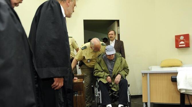 Der wegen Beihilfe zum Mord angeklagte US-Bürger John »Iwan« Demjanjuk wird in München von Polizisten in den Gerichtssaal des Der wegen Beihilfe zum Mord angeklagte US-Bürger John »Iwan« Demjanjuk wird in München von Polizisten in den Gerichtssaal des