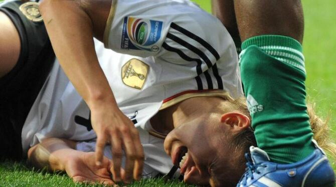 Babett Peter liegt von einer Nigerianerin gefoult auf dem Spielfeld.