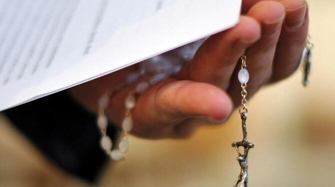 Ein Priester hält einen Rosenkranz und eine bischöfliche Erklärung zu den Missbrauchsfällen durch Jesuiten-Pater in der Hand.