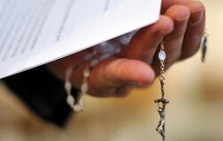Ein Priester hält einen Rosenkranz und eine bischöfliche Erklärung zu den Missbrauchsfällen durch Jesuiten-Pater in der Hand.