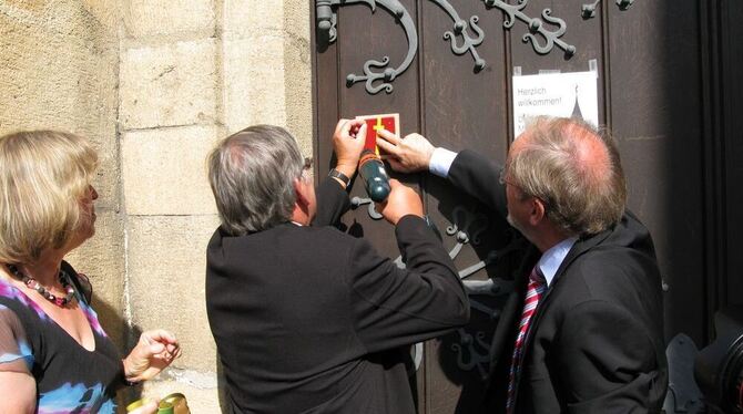 Die Bürgermeister Genaz und Heß (von links) schraubten das Symbol des Martinswegs ans Kirchentor. GEA-FOTO: BARAL Die Bürgermeister Genaz und Heß (von links) schraubten das Symbol des Martinswegs ans Kirchentor. GEA-FOTO: BARAL