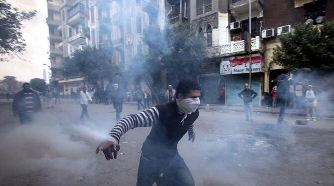Ein Jugendlicher versucht eine Tränengasgranate der Sicherheitskräfte zurückzuwerfen. Foto: Khaled Elfiqi
