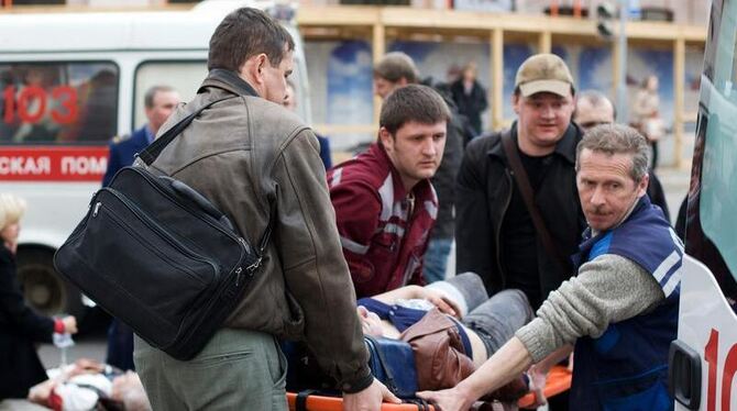 Rettungskräfte und Passanten tragen im April 2011 in Minsk einen Verletzten zu einem Rettungswagen. Foto: Anton Motolko