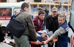Rettungskräfte und Passanten tragen im April 2011 in Minsk einen Verletzten zu einem Rettungswagen. Foto: Anton Motolko