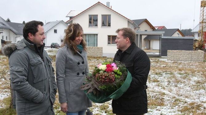Bürgermeister Mike Münzing (rechts) beglückwünschte die neuen Grundeigentümer, Slawa und Valentina Hartmann zum Kauf mit einem B